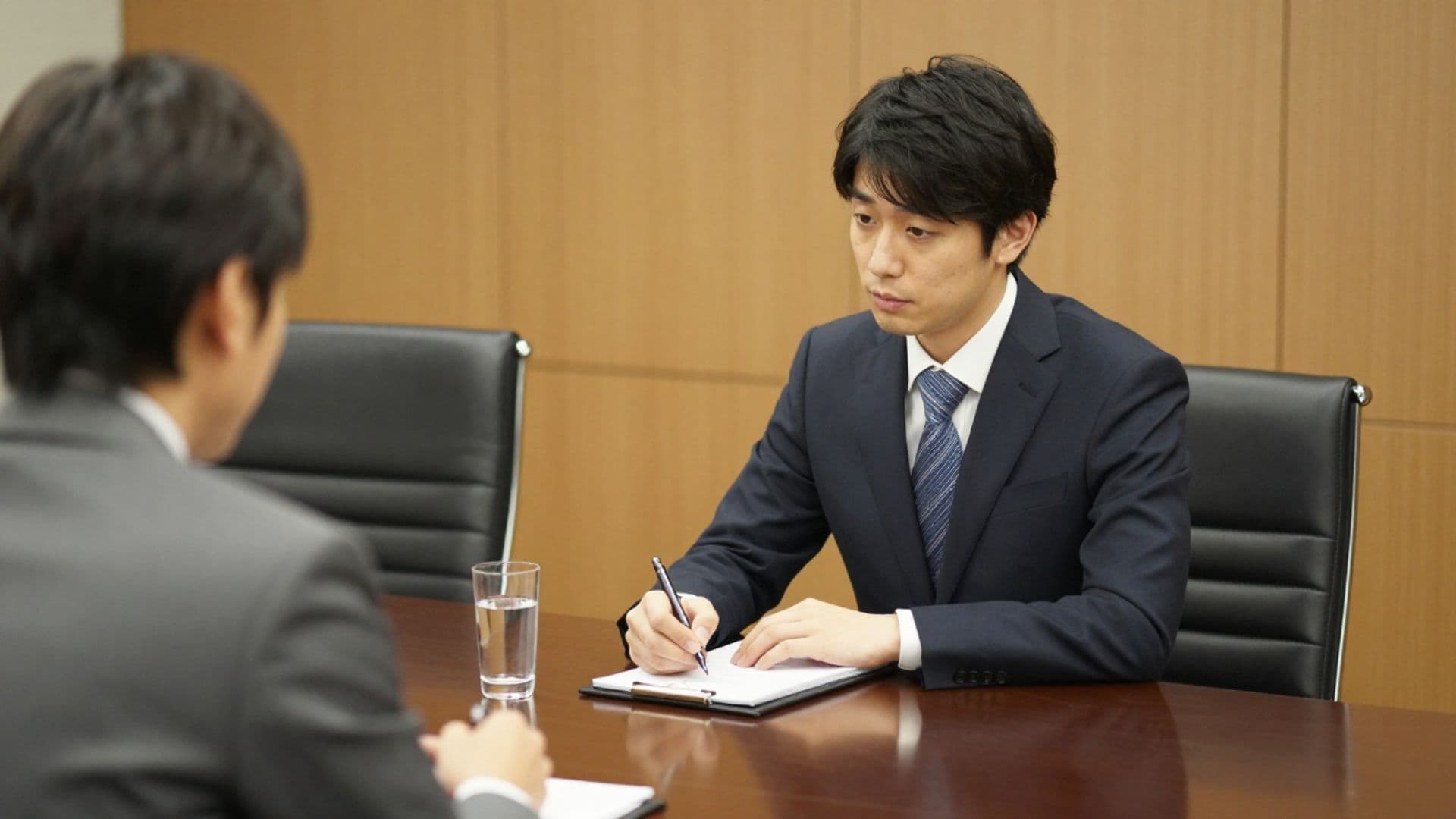 メモを取りながら話を聞く男性